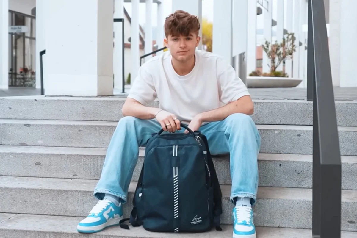 Lewinray sitzt mit dem Lewinray-Rucksack auf einer Treppe